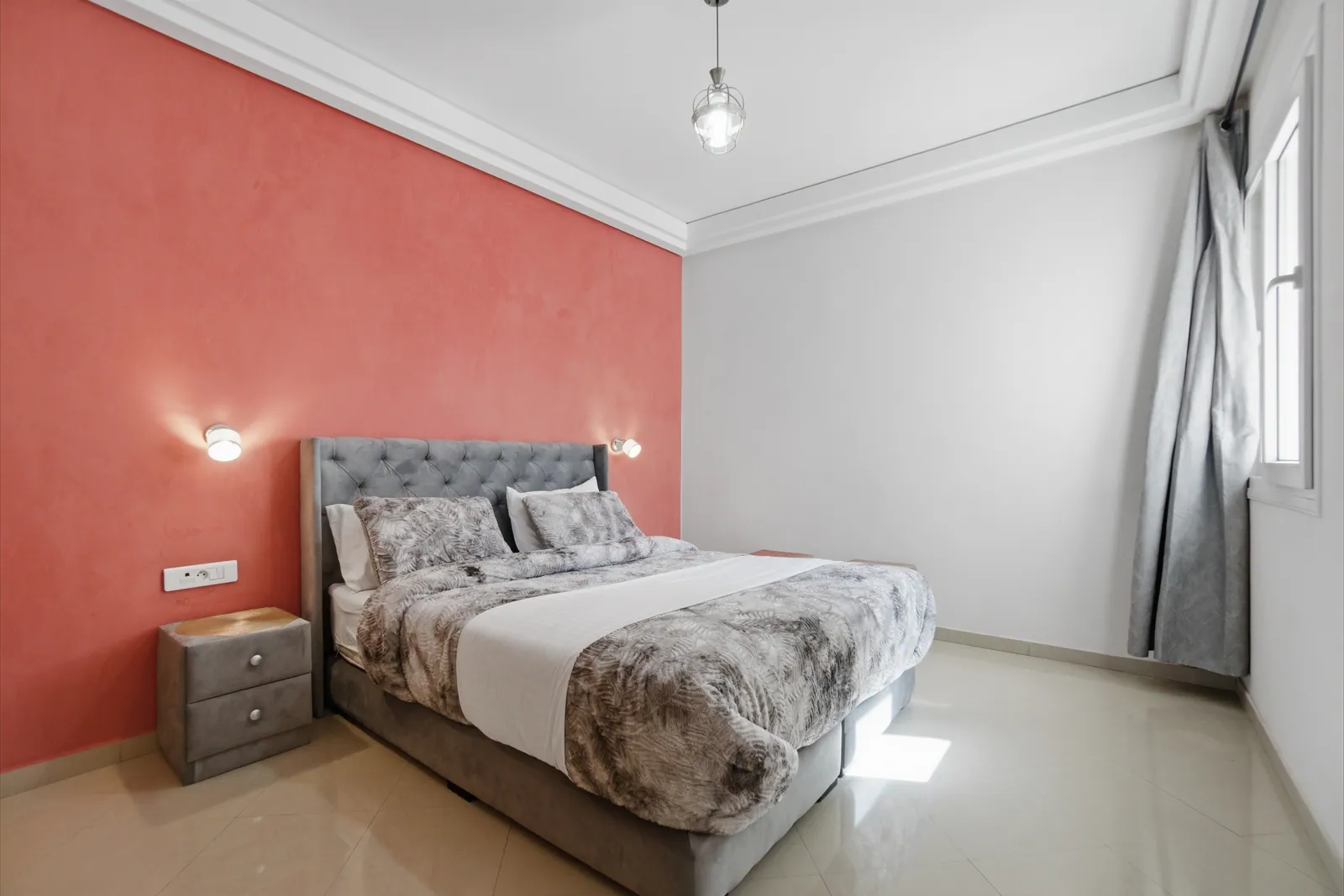 Master bedroom with queen bed and coral accent wall